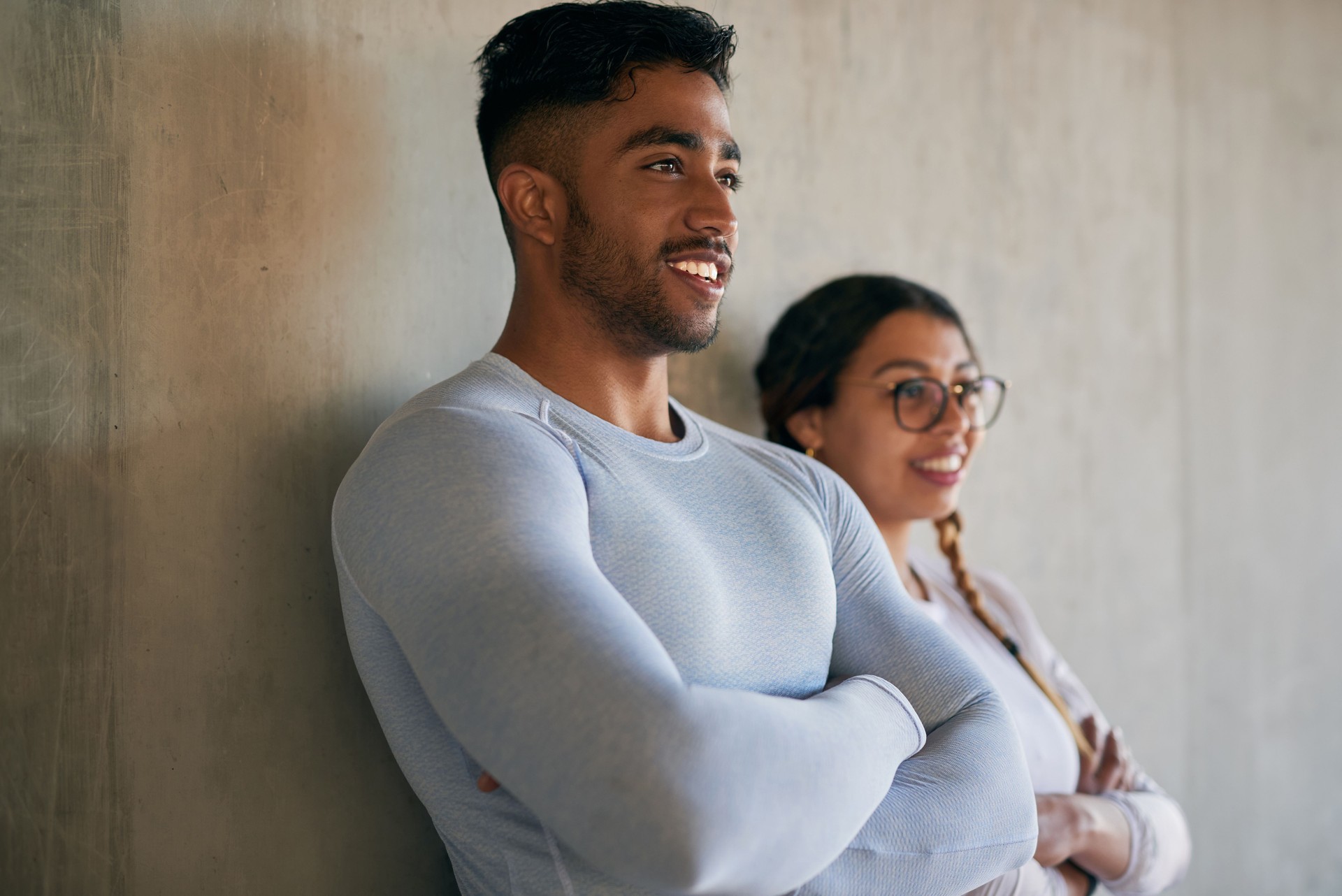 Shot of a sporty young man and woman standing with their arms crossed while exercising outdoors