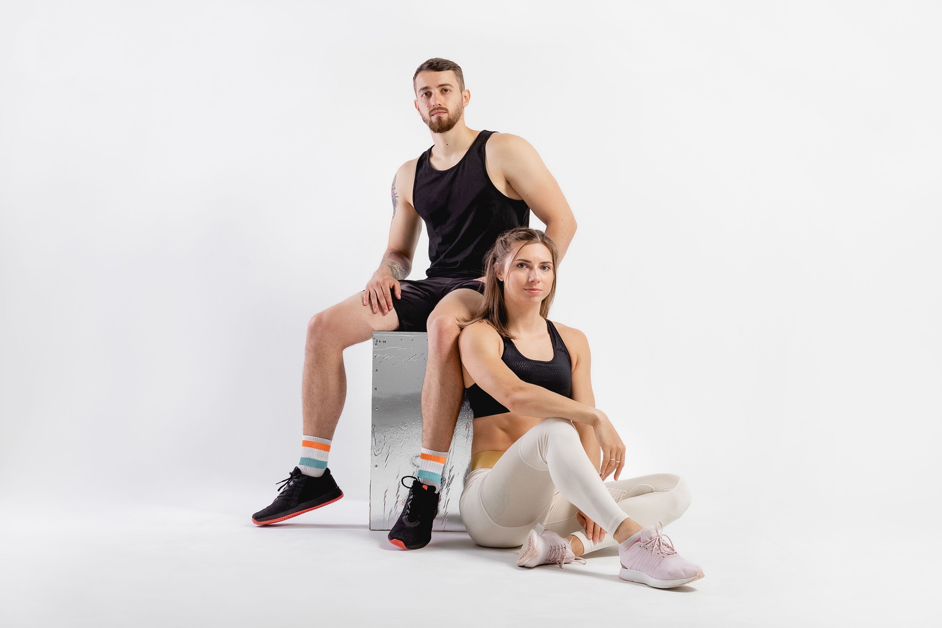 Group portrait of man and woman in studio. Fitness concept for exercise and muscular build. Professional athlete, fit photography. Two people doing sport and sitting on the cube